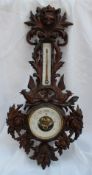 A 19th century Black Forest carved oak barometer carved with a fox mask and birds with a mercury