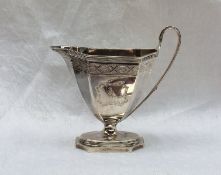 A George III silver cream jug of octagonal panelled tapering form on a spreading foot,