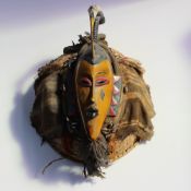 An African mask display, with a yellow head with stork surmount,