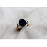 A sapphire and diamond ring the central oval faceted sapphire measuring 12mm x 9mm flanked by two