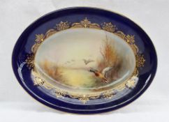 A Royal Worcester porcelain oval dish painted with a mallard and other ducks in flight from a pond