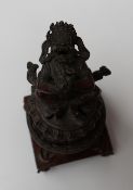 A Sino Tibetan bronze incense burner with Buddhist symbols with the deity Jambhala seated on top,