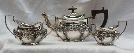 An Edward VII silver three piece tea set, embossed with flowers and scrolls, on an oval foot,