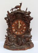 A late 19th / early 20th century Black Forest Cuckoo bracket clock the surmount carved with a