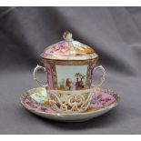 A 19th century continental twin handled chocolate cup, cover and saucer painted with panels of