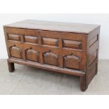 An 18th century oak coffer the planked rectangular top above an eight panel front on stiles,