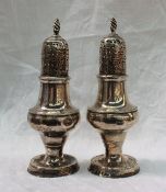 A pair of George III silver sugar sifters with flame finials and pierced domed lids above a ring