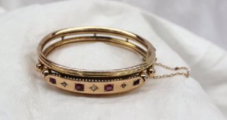 A yellow metal hinged bangle set with three rubies and three diamonds, approximately 15 grams