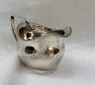 A George III silver cream jug, of oval form with a band of leaves on an oval foot, London, 1810,