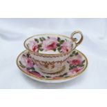 A Nantgarw porcelain teacup and saucer painted with large roses, dentil bands and gilt seaweed