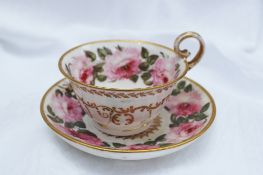 A Nantgarw porcelain teacup and saucer painted with large roses, dentil bands and gilt seaweed