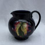 A Moorcroft pottery jug decorated in the grape and leaf pattern to a Royal blue ground, impressed