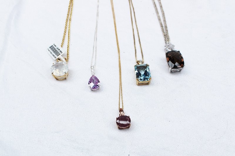 A ruby and diamond pendant together with four other semi precious set pendants