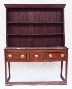 An 18th century oak dresser, the rack with a moulded cornice above two shelves and a planked back,
