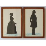 A pair of 19th century cut paper and painted silhouettes depicting a gentleman and a lady holding a