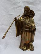 A bronze model of a Chinese Deity, holding a staff  in one hand and a shoe in the other,