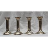 A set of four Edwardian silver candlesticks, of cylindrical form with line decoration,