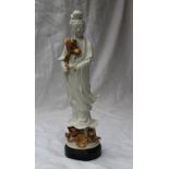 A Chinese Blanc-de-Chine figure of Guanyin, with flowing robes standing holding a lotus flower,