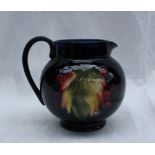 A Moorcroft pottery jug decorated in the grape and leaf pattern to a Royal blue ground, impressed