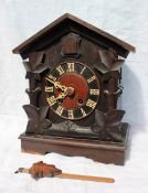 A Black forest cuckoo mantle clock with a pitched roof, carved leaf sides and a plinth base,