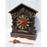 A Black forest cuckoo mantle clock with a pitched roof, carved leaf sides and a plinth base,