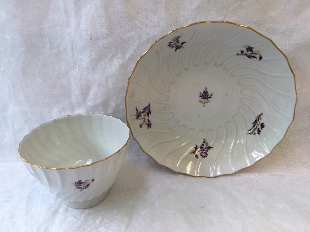 A Worcester Barr period tea bowl and saucer of wave form with a gilt decorated rim painted with