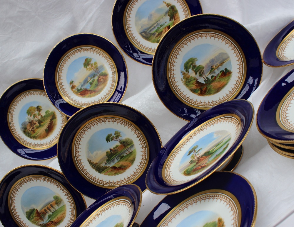 A 19th century porcelain dessert set each piece painted with landscape scenes within a Royal blue