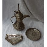 A white metal teapot, with a domed pointed lid, the body embossed with leaves and flowers,