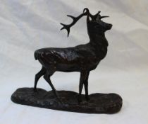 A Bronze stag - standing with head raised on an oval naturalistic base,