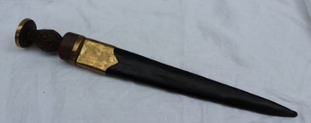 A short sword, with a brass capped carved wooden handle and a brass and leather scabbard,