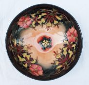 A Moorcroft pottery bowl decorated in the Oberon pattern with flower heads to a graded ground,