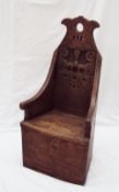 An oak child's chair with a carved back, solid seat and sides,