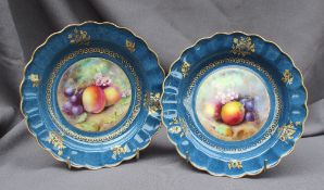 A pair of Royal Worcester bowls of shaped circular form with a gilt border, painted to the centre