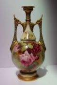 A Royal Worcester porcelain twin handled vase with a pair of pierced gilt decorated handles, the