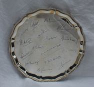 An Elizabeth II silver salver with a beaded rim, bears signatures to the main plate, on four ball