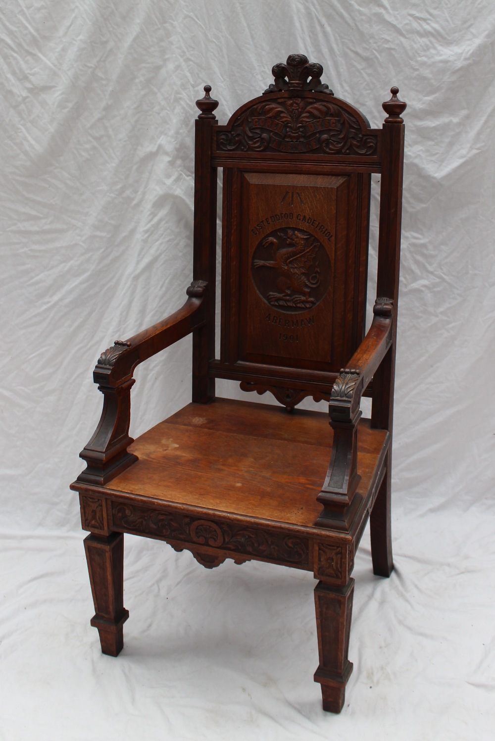 An early 20th century oak Eisteddfod Chair, carved with the Prince of Wales feathers to the top, the