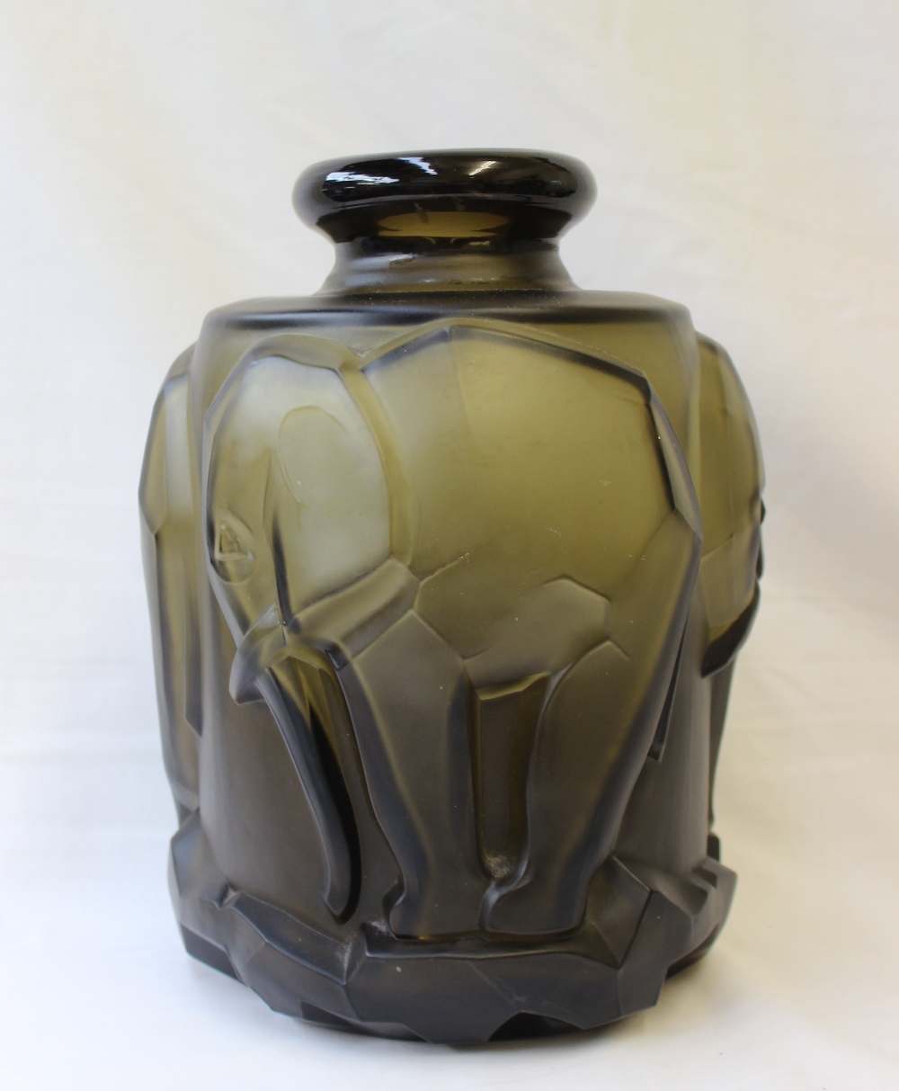 An Art Deco style green glass vase, moulded with elephants on a rocky base,