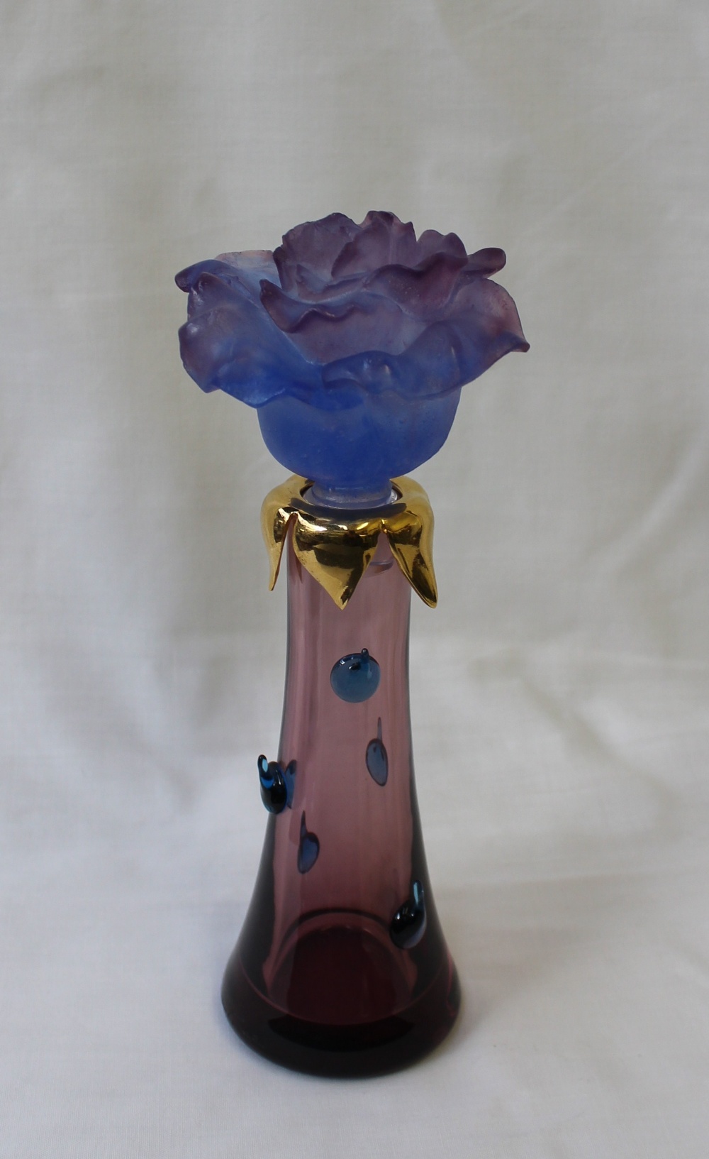 A Daum scent bottle, with a floral glass stopper, gilt top and tapering cylindrical bottle with