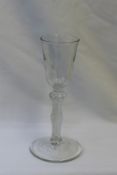 An 18th century wine glass with a tapering bowl above a knopped air twist stem on a spreading foot,