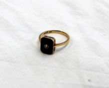 A diamond and onyx panel ring, the diamond set to the centre of a rectangular onyx panel on a yellow