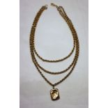 A yellow metal three strand Albert chain marked 9ct , together with a 9ct yellow gold locket,