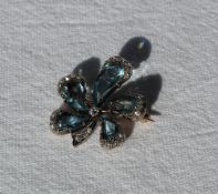 An aquamarine and diamond brooch of floral form with five tear drop shaped aquamarines, the centre
