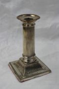 A silver desk candlestick, the beaded sconce above a ribbed ionic column on a square base,