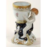 FIGURA DE QUERUBÍN sosteniendo recipiente, en porcelana decorada. Altura: 22 cm.