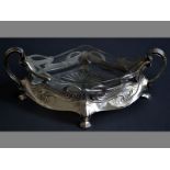 AN ART NOUVEAU SILVERPLATE CENTRE PIECE with twin-handles, clear glass bowl, standing on four hoof