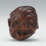 Carved Netsuke of an Oni Mask 1-7/8" x 1-3/4"Carved wood of an oni mask, black inlaid eyes, tongue