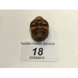 A tiny carved wooden netsuke of a face.