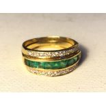 A diamond and emerald ring in a yellow metal band two part ring. 7.6 g