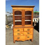 A pine dresser with glazed top and two drawer over three chest of drawers below.