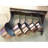 A set of graduated copper pans with hanging rack.